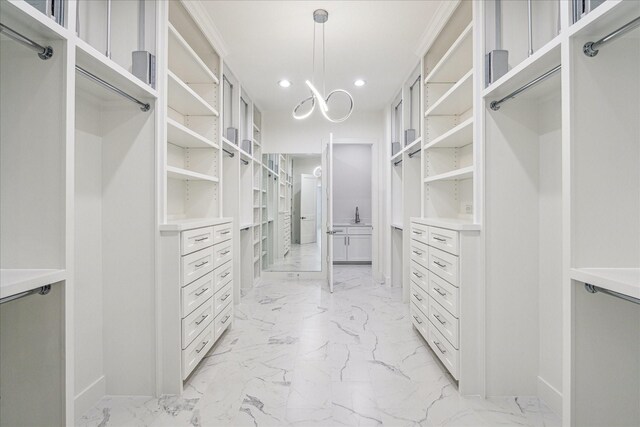 walk in closet with marble finish floor and a notable chandelier