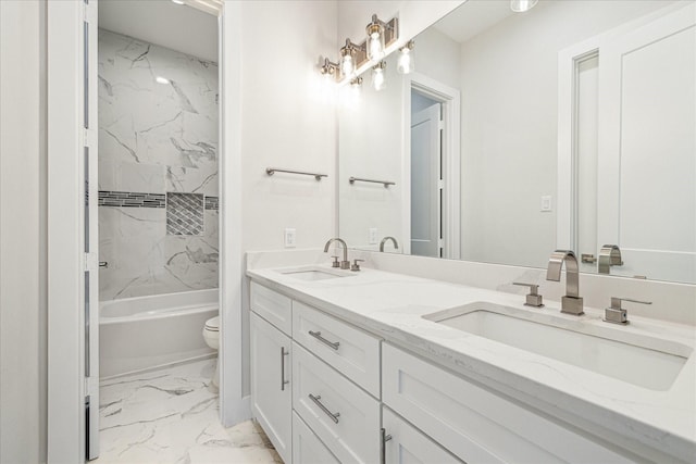 bathroom with marble finish floor, double vanity, a sink, and toilet