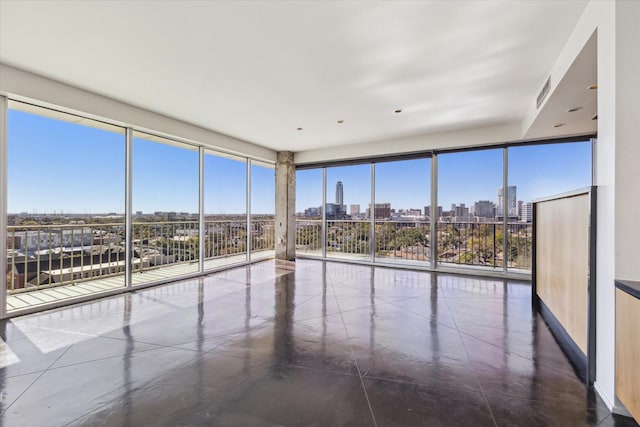 empty room featuring a view of city, visible vents, a wall of windows, and a wealth of natural light