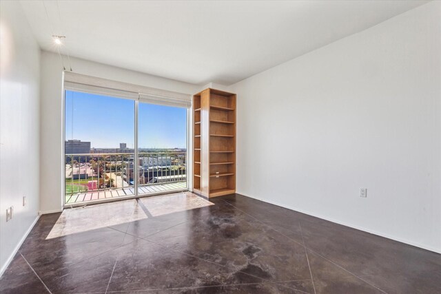 unfurnished room featuring a view of city, baseboards, and concrete flooring