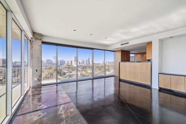 empty room featuring floor to ceiling windows, a city view, visible vents, and marble finish floor