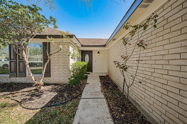 entrance to property featuring brick siding and visible vents