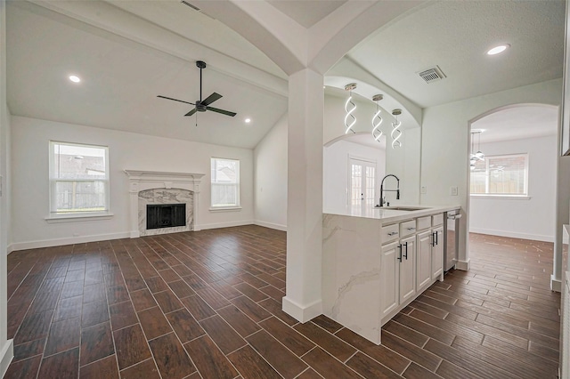 kitchen featuring visible vents, wood tiled floor, lofted ceiling with beams, a fireplace, and a sink