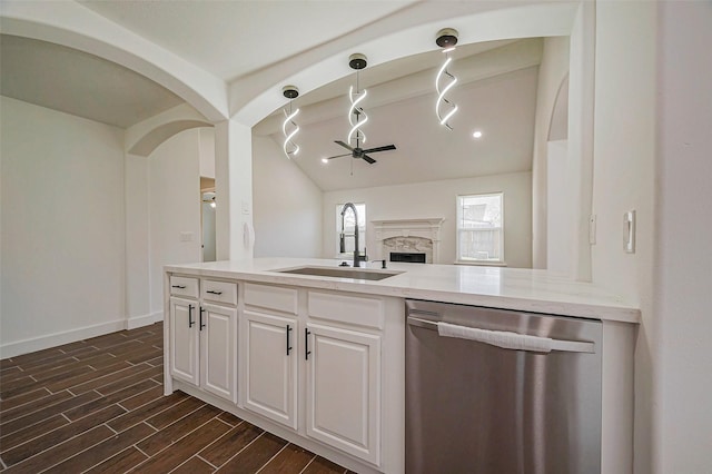 kitchen with a ceiling fan, wood tiled floor, a high end fireplace, a sink, and dishwasher