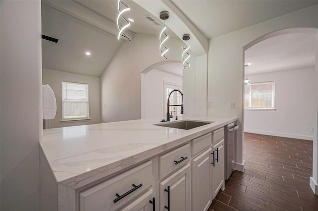 kitchen with a sink, baseboards, light stone counters, white cabinetry, and dark wood-style flooring