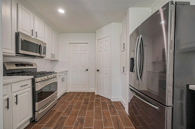 kitchen with tasteful backsplash, appliances with stainless steel finishes, white cabinets, light countertops, and wood tiled floor