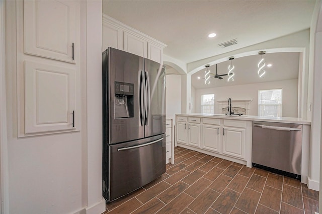 kitchen featuring visible vents, wood tiled floor, a sink, stainless steel appliances, and white cabinets