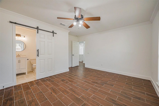 unfurnished bedroom with visible vents, dark wood-type flooring, a barn door, and ornamental molding