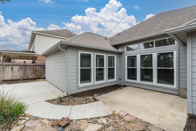 back of house featuring a patio, a shingled roof, and fence