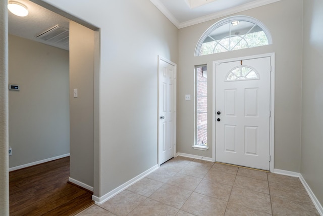 foyer entrance featuring a wealth of natural light, light tile patterned floors, crown molding, and baseboards