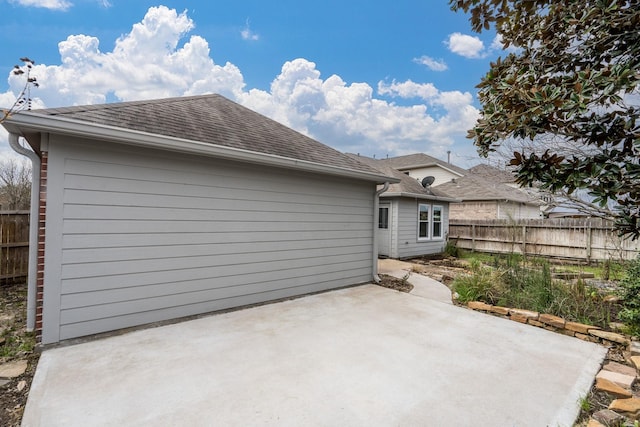 rear view of house featuring a patio area, fence, and roof with shingles