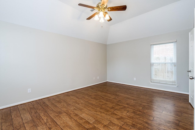 empty room with dark wood finished floors, vaulted ceiling, a ceiling fan, and baseboards