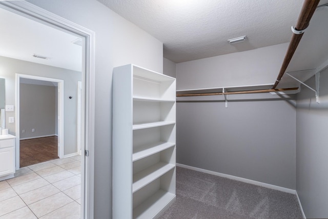 walk in closet featuring light tile patterned floors, visible vents, and light carpet