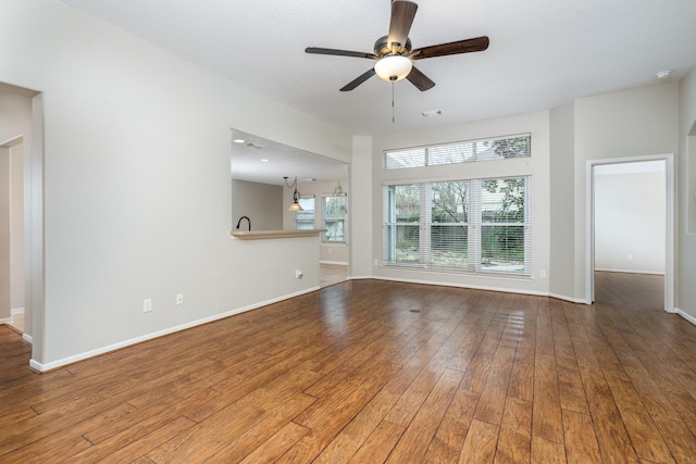 unfurnished living room with visible vents, a ceiling fan, baseboards, and hardwood / wood-style floors