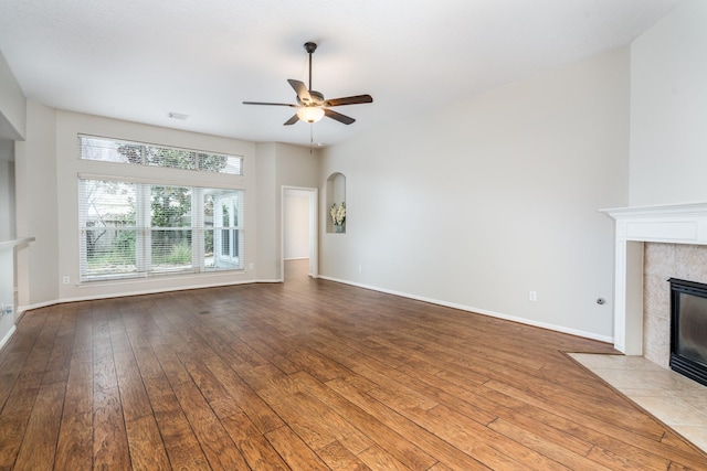 unfurnished living room with visible vents, baseboards, a tiled fireplace, hardwood / wood-style flooring, and a ceiling fan