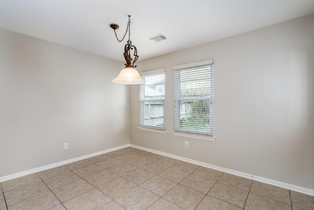 empty room featuring light tile patterned floors, visible vents, and baseboards