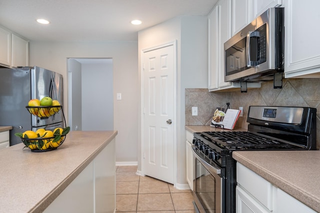 kitchen featuring light tile patterned flooring, decorative backsplash, appliances with stainless steel finishes, and white cabinetry