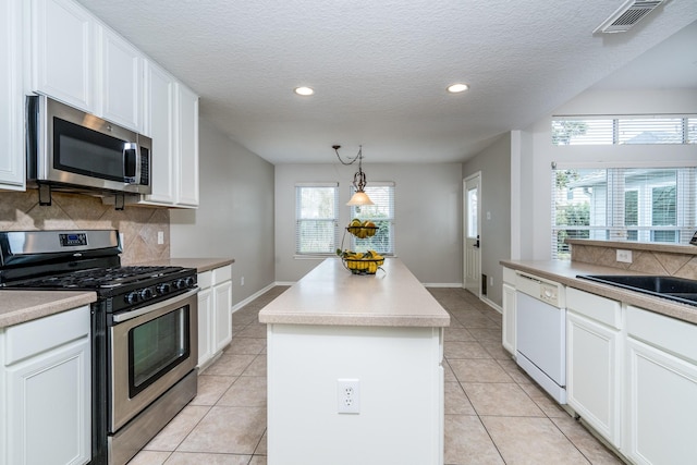 kitchen with visible vents, decorative backsplash, appliances with stainless steel finishes, white cabinetry, and a center island