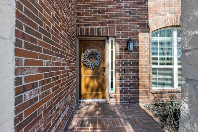 view of exterior entry featuring brick siding