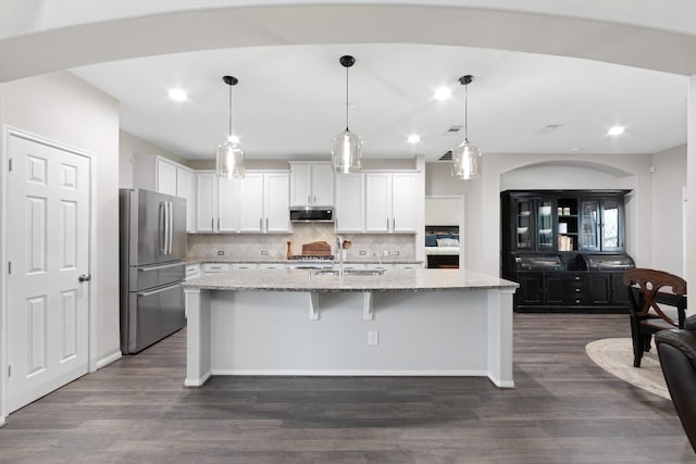 kitchen featuring stainless steel appliances, dark wood-style flooring, a sink, white cabinetry, and light stone countertops