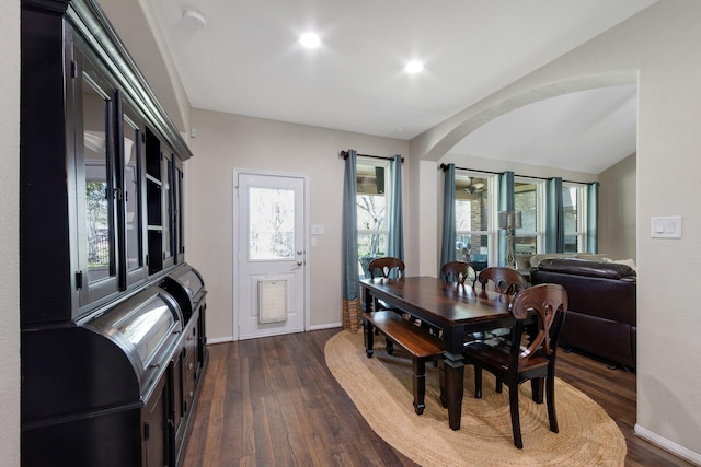 dining room featuring arched walkways, dark wood finished floors, recessed lighting, vaulted ceiling, and baseboards