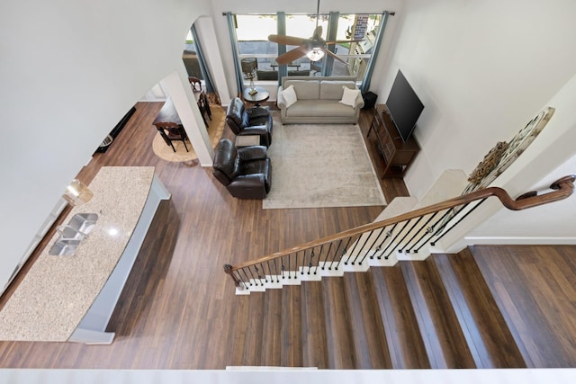 living area with a ceiling fan, stairs, arched walkways, and wood finished floors