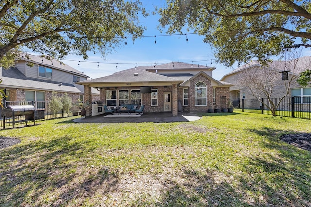 rear view of property with a fenced backyard, heating fuel, a yard, a patio area, and brick siding