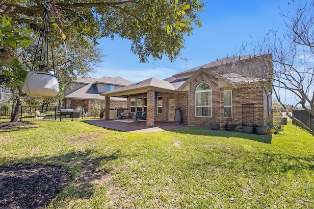 back of house with fence private yard, a patio area, a yard, and brick siding