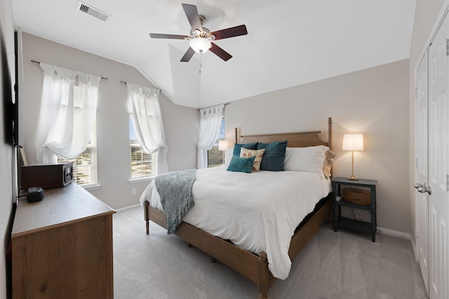 bedroom with baseboards, visible vents, light colored carpet, vaulted ceiling, and a closet