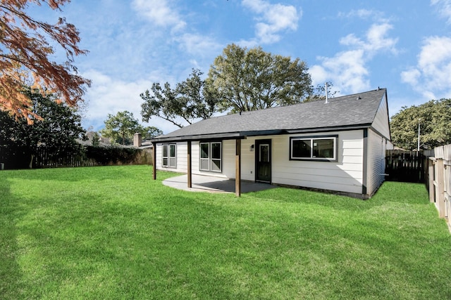 back of property featuring roof with shingles, a lawn, a patio area, and a fenced backyard