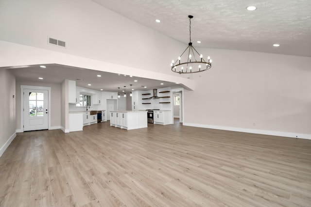 unfurnished living room featuring baseboards, visible vents, an inviting chandelier, light wood-type flooring, and recessed lighting