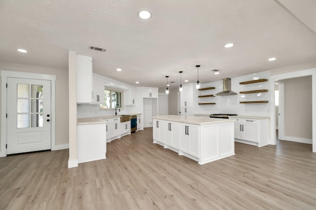 kitchen featuring white cabinets, visible vents, wall chimney range hood, and open shelves