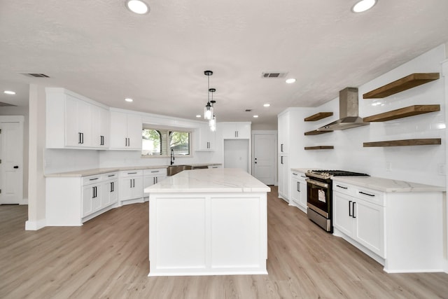 kitchen with visible vents, wall chimney exhaust hood, light stone countertops, open shelves, and stainless steel range with gas stovetop