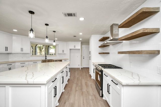 kitchen with open shelves, visible vents, gas stove, a sink, and wall chimney range hood