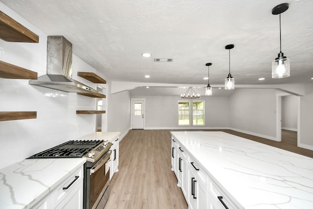 kitchen with open shelves, backsplash, light wood-style floors, gas stove, and wall chimney exhaust hood