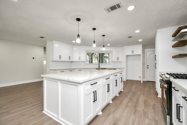 kitchen featuring light wood-style floors, visible vents, open shelves, and gas range