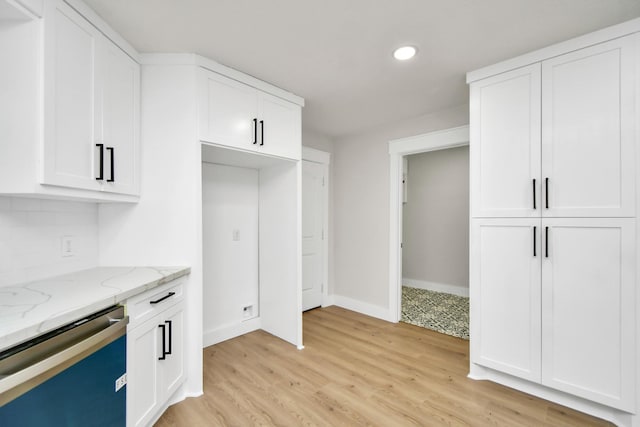 kitchen with dishwasher, light stone counters, light wood-style floors, white cabinetry, and backsplash