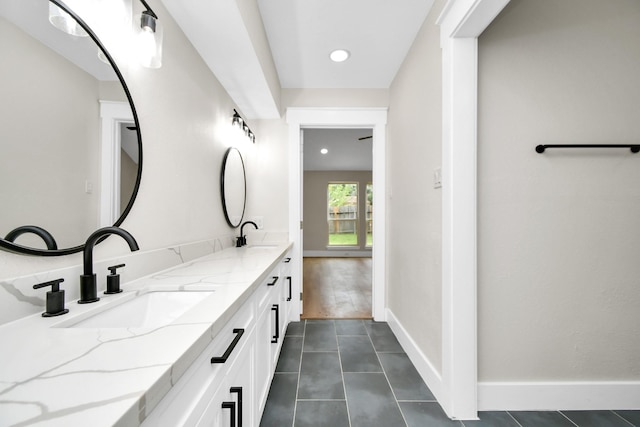 bathroom with double vanity, tile patterned flooring, a sink, and baseboards