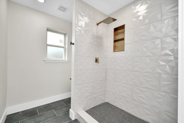 bathroom featuring baseboards, a tile shower, visible vents, and tile patterned floors