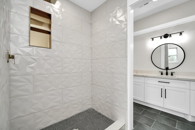 bathroom featuring visible vents, tiled shower, vanity, and tile patterned floors