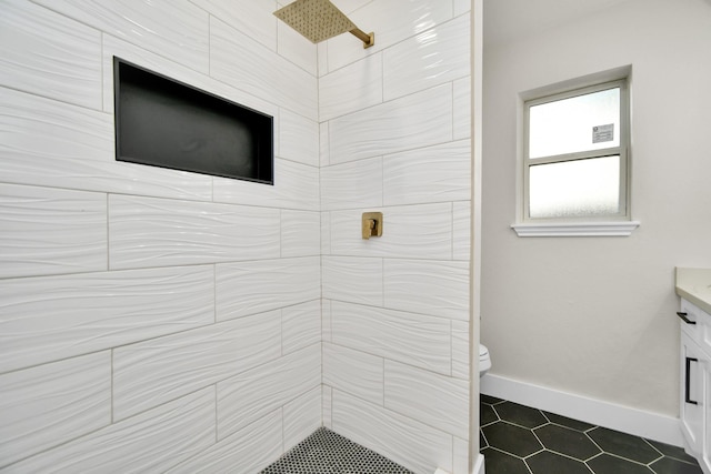 full bathroom featuring toilet, a tile shower, vanity, baseboards, and tile patterned floors