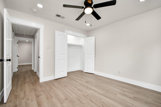 unfurnished bedroom with attic access, visible vents, baseboards, light wood-style floors, and a closet