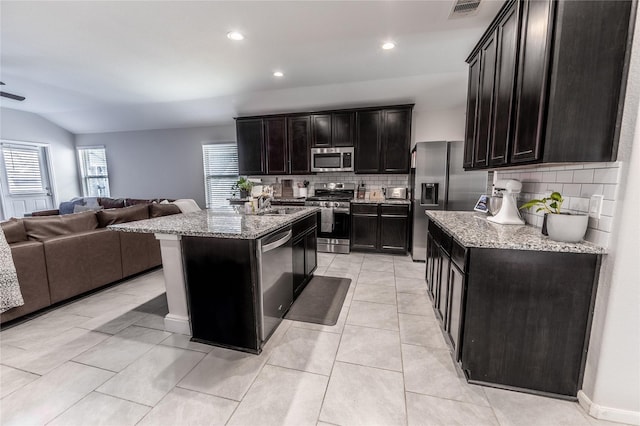 kitchen featuring stainless steel appliances, open floor plan, visible vents, and light stone countertops