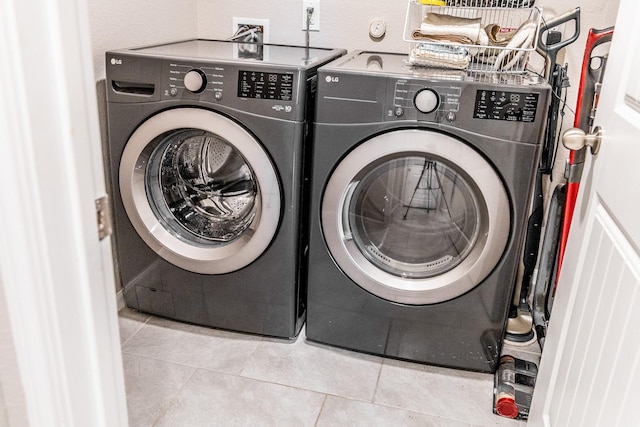 laundry room with tile patterned floors, laundry area, a textured wall, and separate washer and dryer