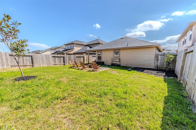 back of property featuring a fenced backyard, a fire pit, and a lawn