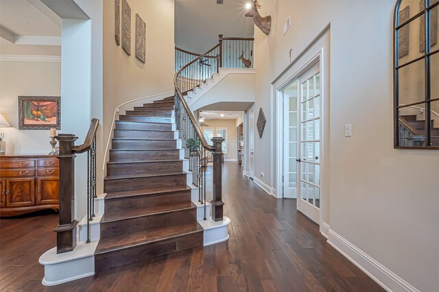 entrance foyer with a towering ceiling, stairs, baseboards, and dark wood-type flooring