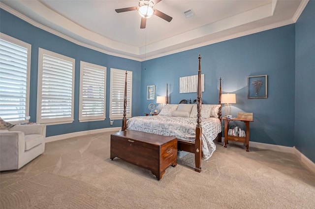 carpeted bedroom with a tray ceiling, crown molding, visible vents, ceiling fan, and baseboards