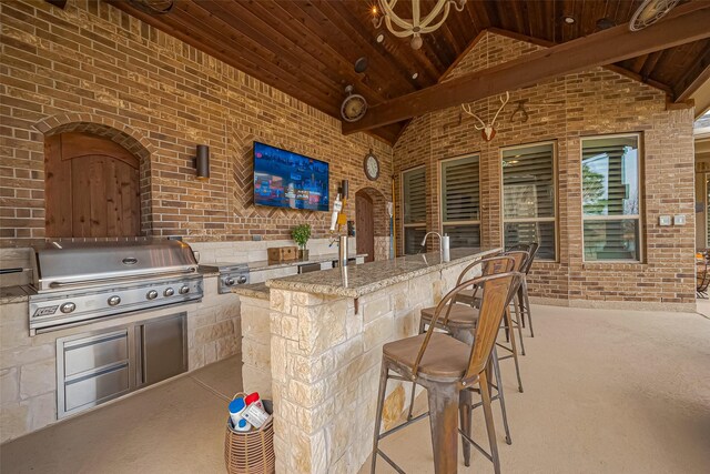 view of patio / terrace featuring outdoor wet bar, exterior kitchen, and area for grilling