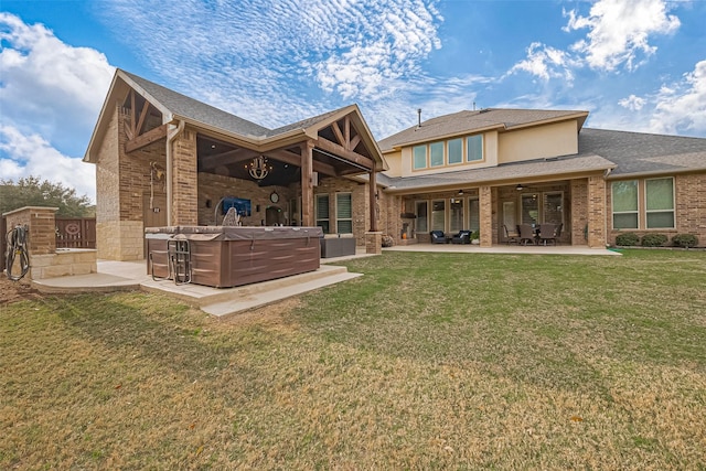 back of property with a hot tub, a lawn, ceiling fan, a patio area, and brick siding