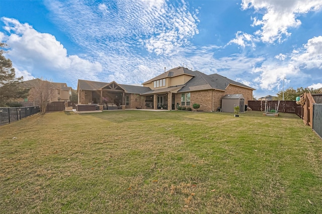 back of property featuring brick siding, a yard, a patio, a fenced backyard, and an outdoor structure